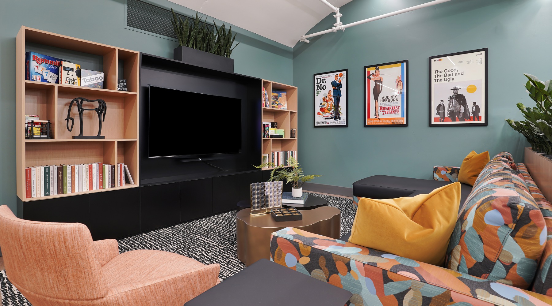 A residential lounge area with couches, a center table, book shelves, and a flatscreen television at The Source at South Temple apartments in Salt Lake City, Utah.
