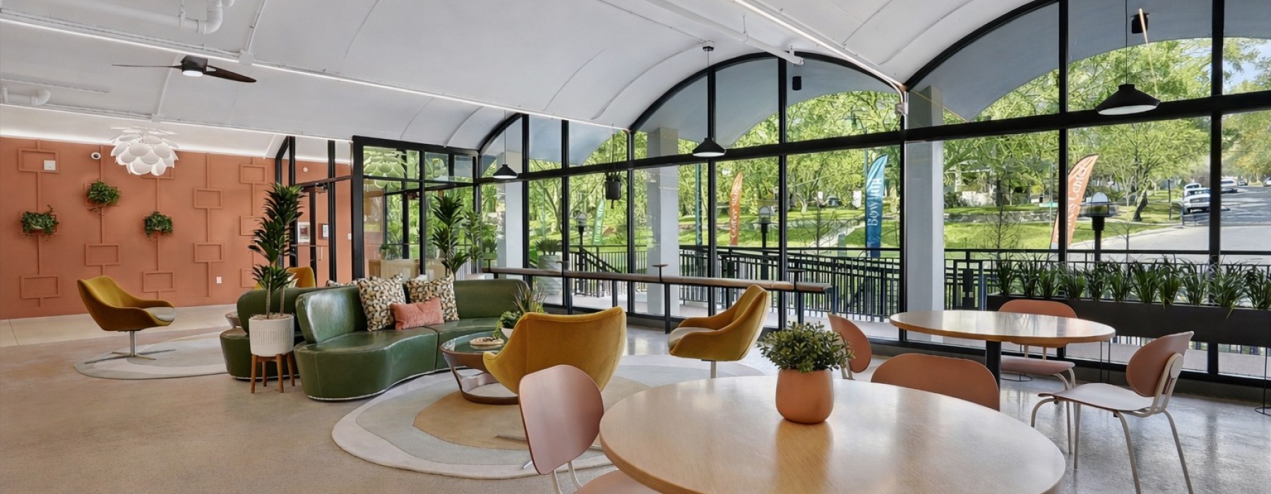A residential lounge area with tables, chairs, and large windows, with views of the outdoors at The Source on South Temple apartments for rent in Salt Lake City, UT.