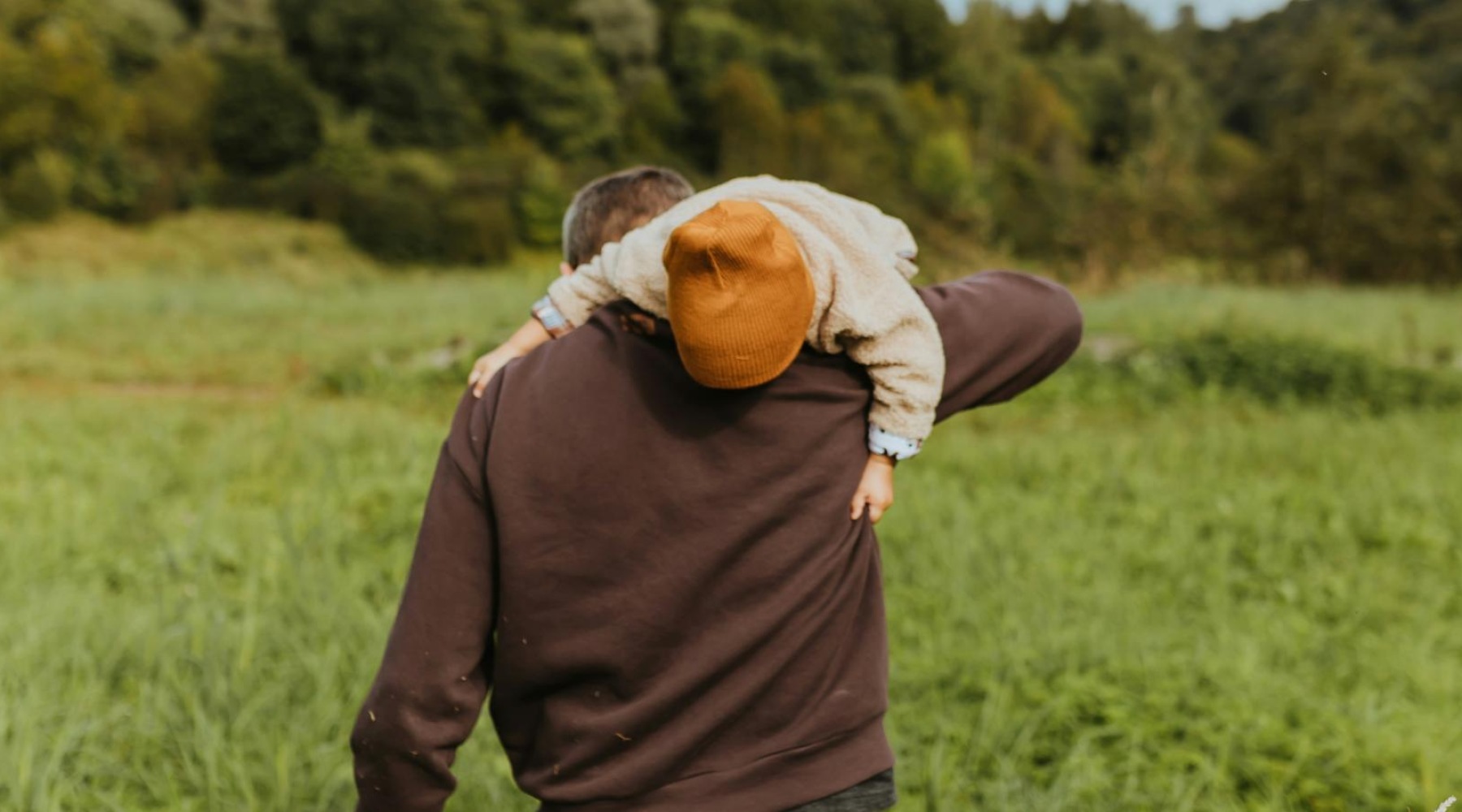 a person walking in a field with a small child