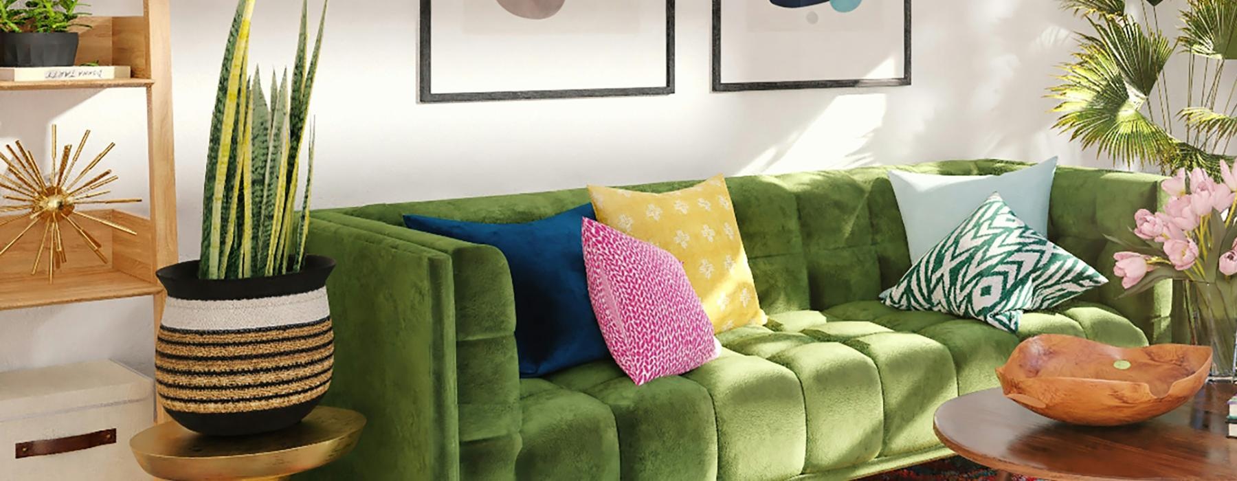 a living room with agreen couch with pillows and side tables